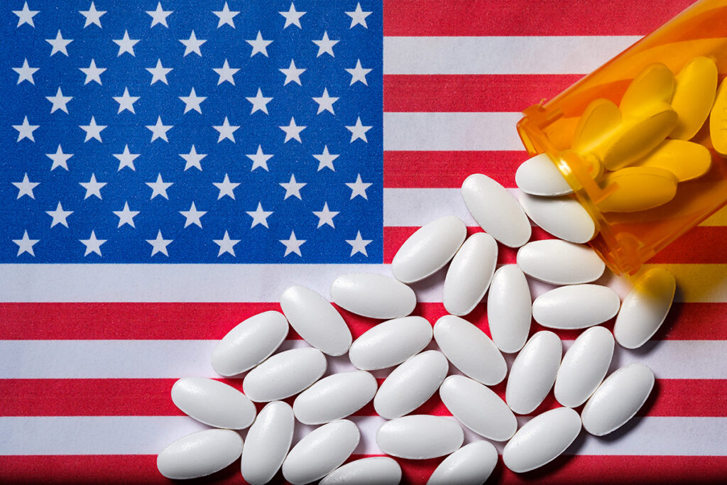 a bottle of prescription pills over an american flag makes people think of the opioid crisis