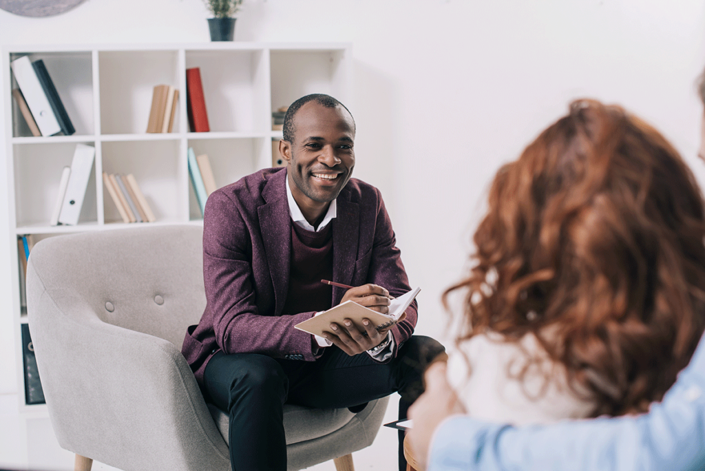 man in purple sweater talking with therapist about balancing an outpatient treatment program