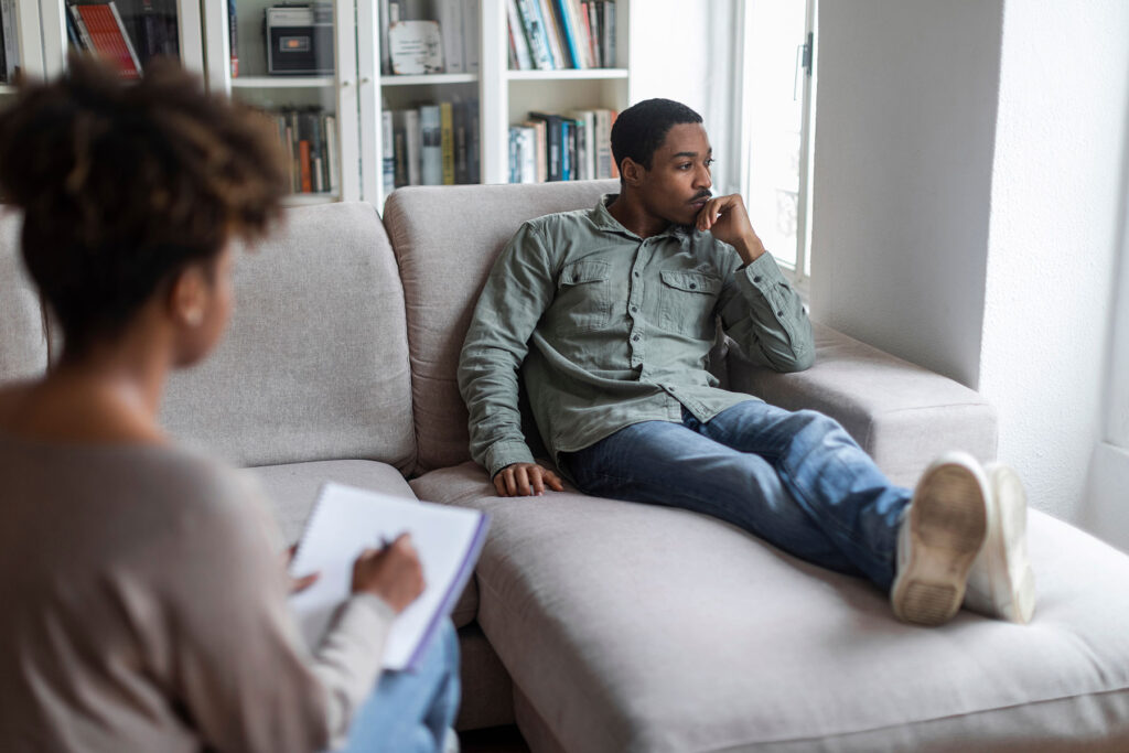 a person sits on a couch and talks to a therapist about what is trauma-informed care