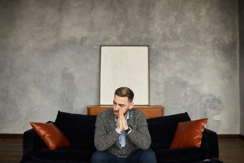 man sitting on couch disappointed because of his relapse