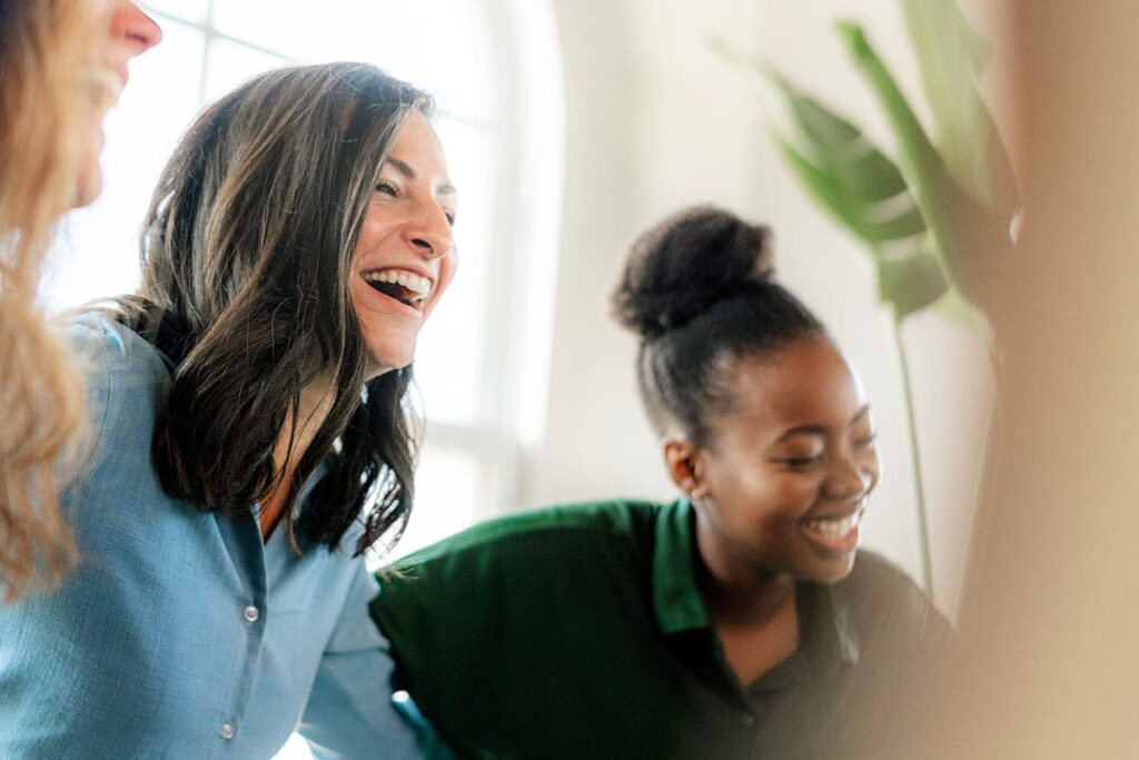 woman in blue shirt and woman in green shirt laughing in a women's rehab center