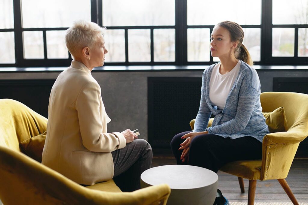 two women sitting in yellow chairs learn why is trauma informed care important