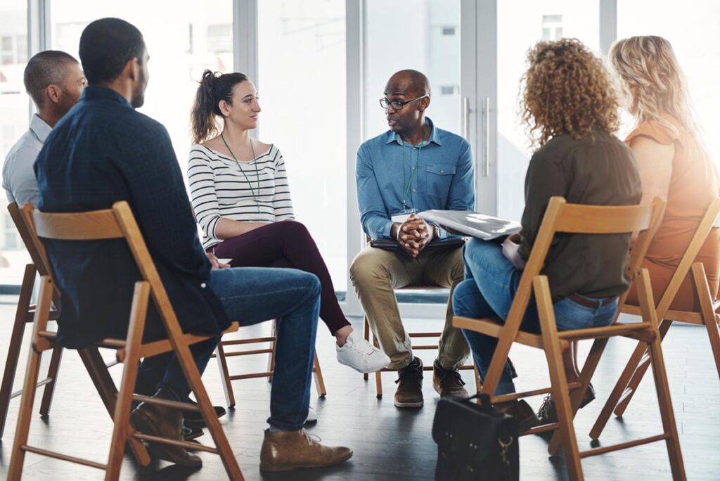 men and women sit in circle in a treatment center for alcohol addiction