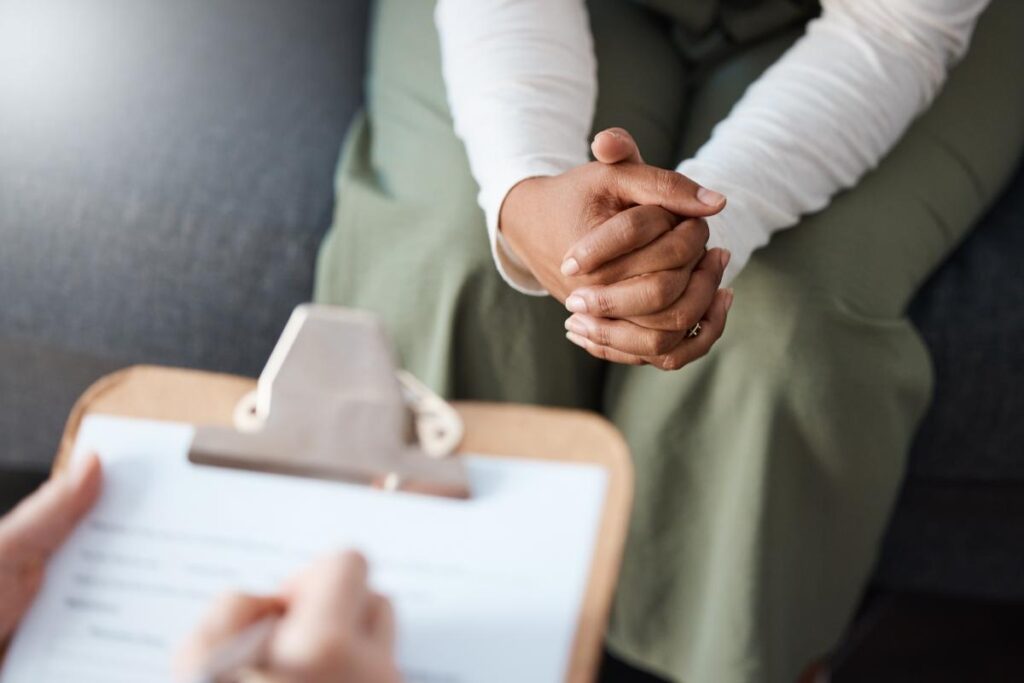 person with hands clasped talks with therapist about what medication-assisted treatment is