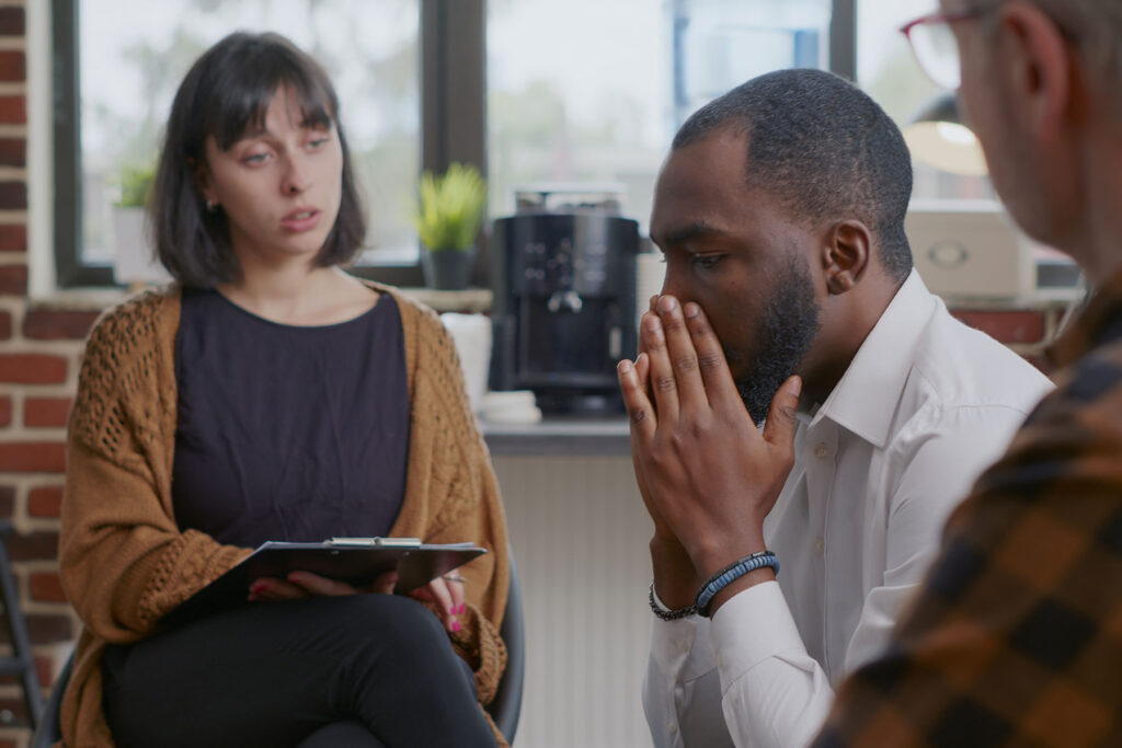 man with head in hands talks with a therapist about heroin signs