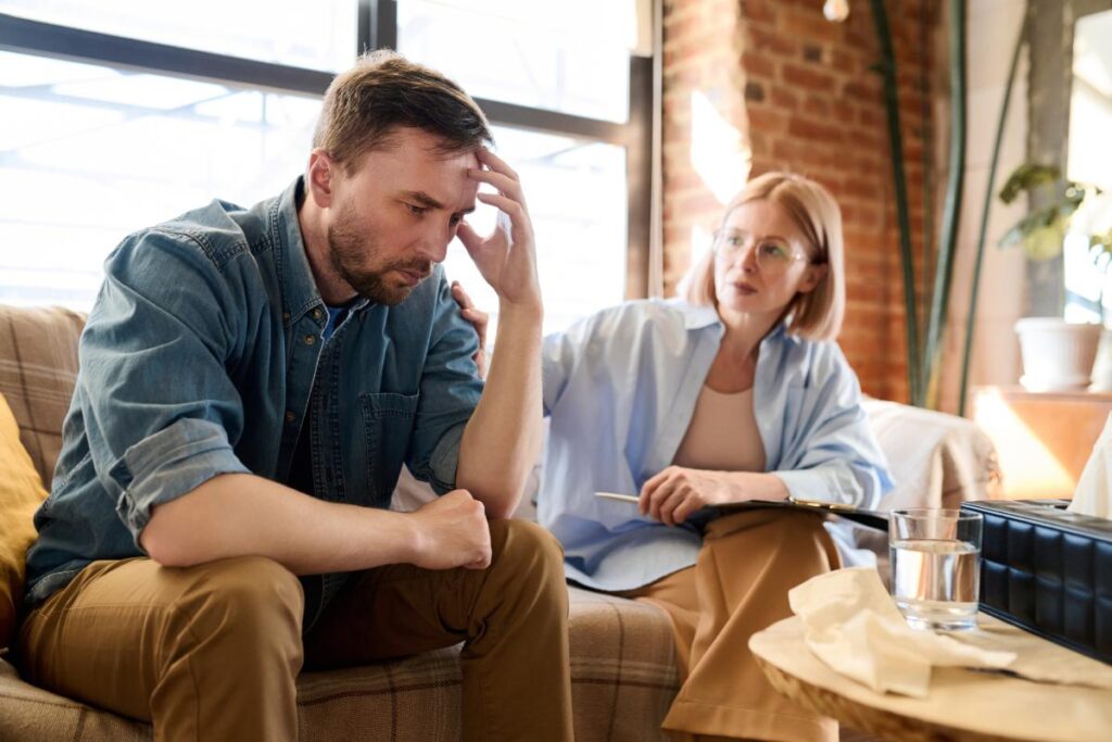 man with head in hands considers the benefits of pain management